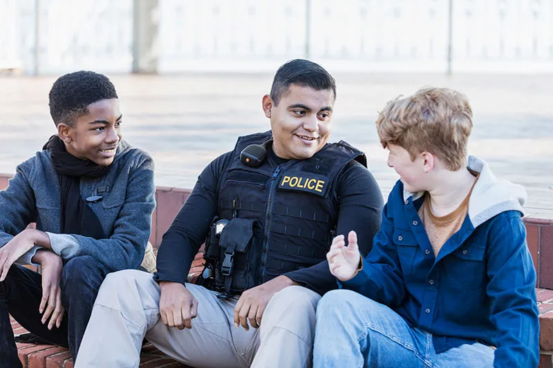 A police officer talking with kids. Bill 1127 will help officers starting in 2023.