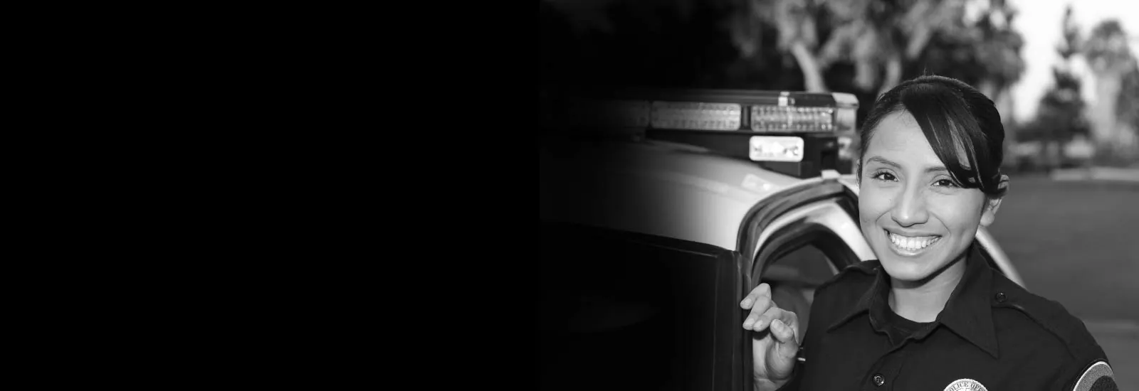 Smiling police officer standing beside a patrol car — representing GEKLAW’s dedication to protecting the rights and benefits of California’s public safety workers.